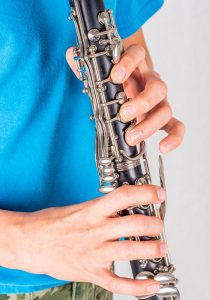 Boy playing a clarinet with a blue shirt on.